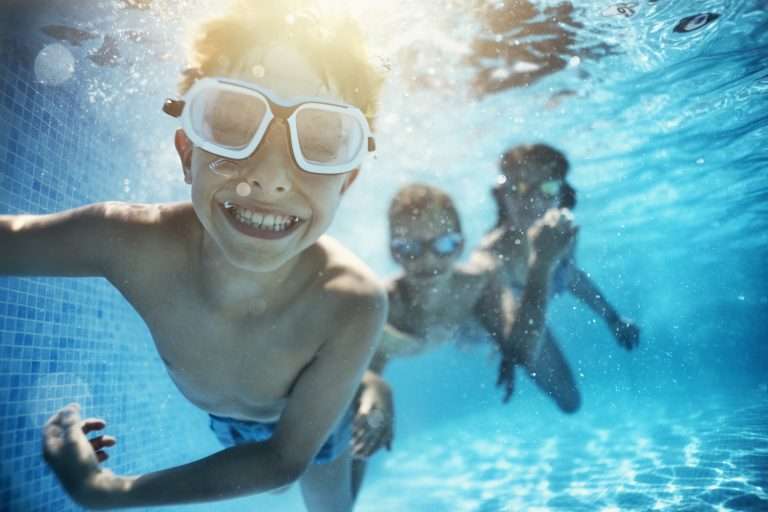 A joyful group of children swimming and playing in a pool, enjoying a refreshing summer day.