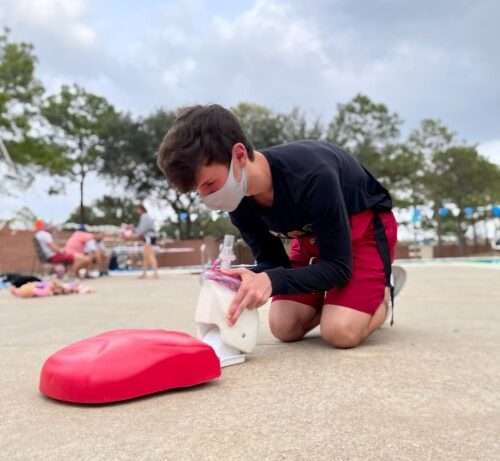 A man kneeling to place a red heart on the ground, symbolizing love and compassion.